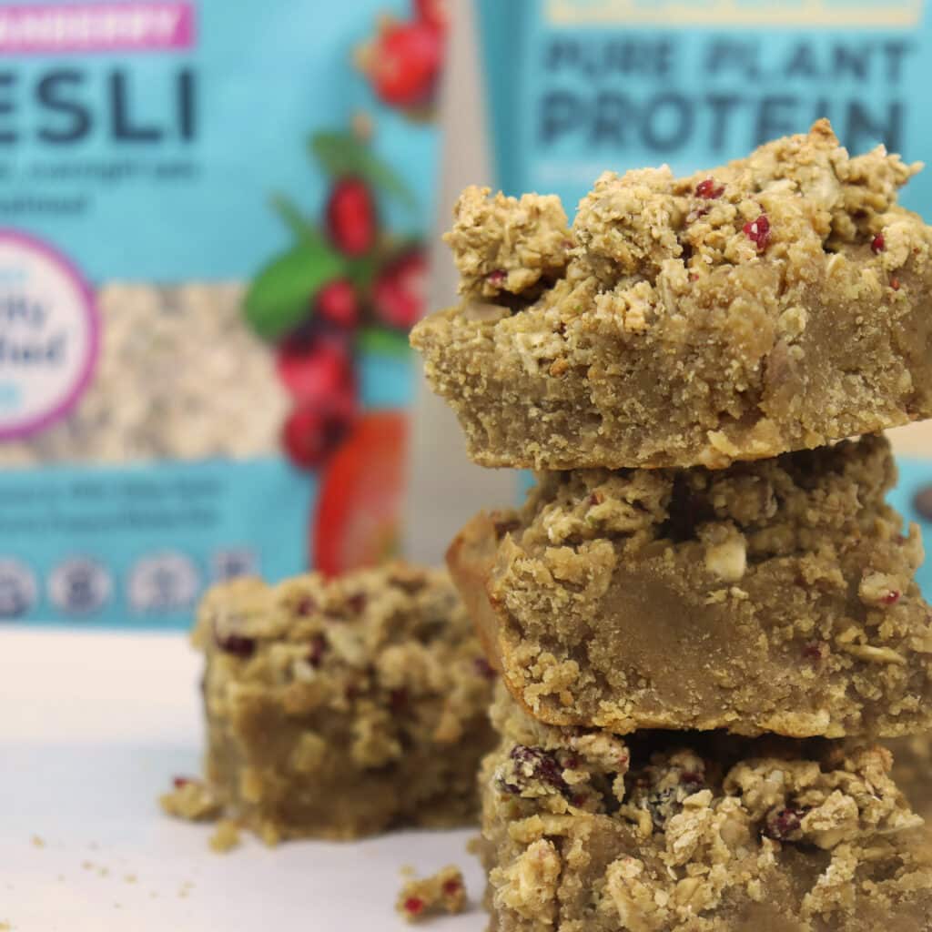 ZEGO Apple Crumble Protein Bars in Stack with Bags in Background